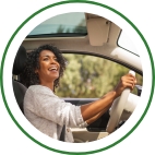 A woman laughs and sits in the driver seat of her vehicle. 
